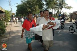 Penguburan jenasah korban gempa. Seorang bapak membopong jenasah seorang anak yang dibungkus kain...