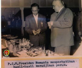 PJM. Presiden Rumania/Gheorghe Gheorg Liu Dej sedang memperhatikan hasil-hasil kerajinan perak sa...