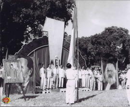 Seorang petugas sedang menaikkan bendera merah putih pada sebuah tiang diikuti peserta Peringatan...