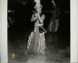 Penari dengan perlengkapan keris yang terselip di perutnya sedang menari dengan iringan gamelan d...