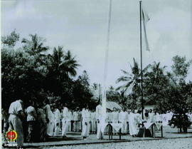 Petugas pengibar bendera sedang mengibarkan Bendera Merah Putih di saksikan peserta upacara .