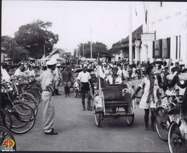 Iring-iringan becak berjalan melewati depan Bank Negara Indonesia dari Alun-Alun Utara terlihat m...