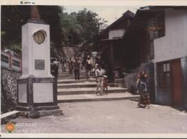 Para pelayat usai menghadiri pemakaman. Tampak latar belakang tugu jam kenang-kenangan Drs. Surasa.