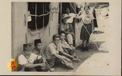 Beberapa anggota Pramuka sedang bersitrirahat di depan tenda.